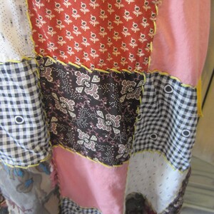 Op de afbeelding: Een patchwork rok met verschillende patronen en kleuren, waaronder rood, roze, zwart en wit. De rok is gemaakt van verschillende stoffen en heeft een rustieke, handgemaakte uitstraling.
