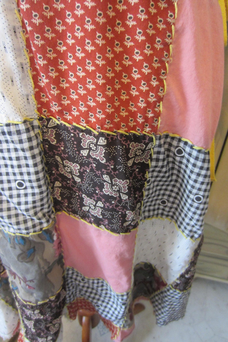 Op de afbeelding: Een patchwork rok met verschillende patronen en kleuren, waaronder rood, roze, zwart en wit. De rok is gemaakt van verschillende stoffen en heeft een rustieke, handgemaakte uitstraling.