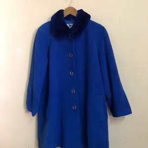 May include: A blue coat with a faux fur collar. The coat has a button closure and a pocket on the left side.