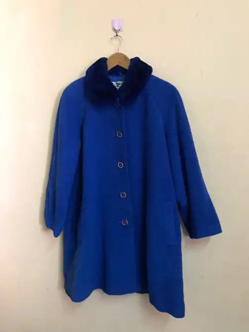 May include: A blue coat with a faux fur collar. The coat has a button closure and a pocket on the left side.