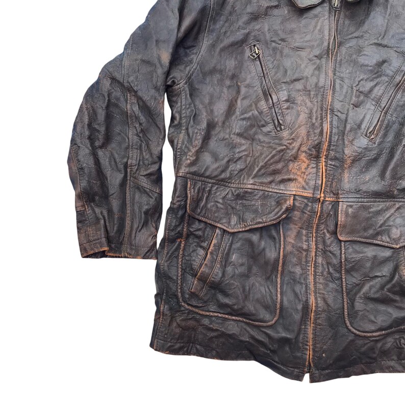 以下が含まれることがあります： ジッパー留めと複数のポケットが付いた茶色の革ジャンパー。ジャケットは使い古したような外観で、厚くて丈夫な素材で作られています。