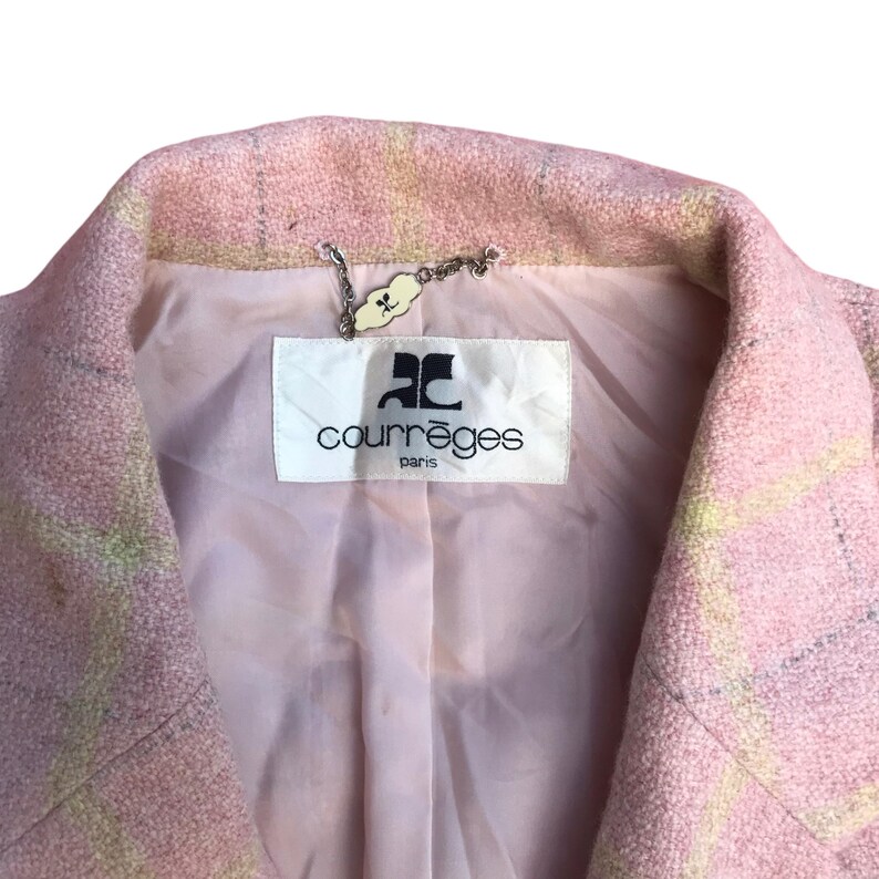 May include: Pink and yellow plaid blazer with a white label that says "Courr&egrave;ges Paris" and a silver chain with a small charm.