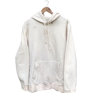 Puede incluir: Una sudadera con capucha blanca con un pequeño logotipo "GAP" bordado en la parte delantera. La sudadera tiene un bolsillo canguro y una capucha con cordón.