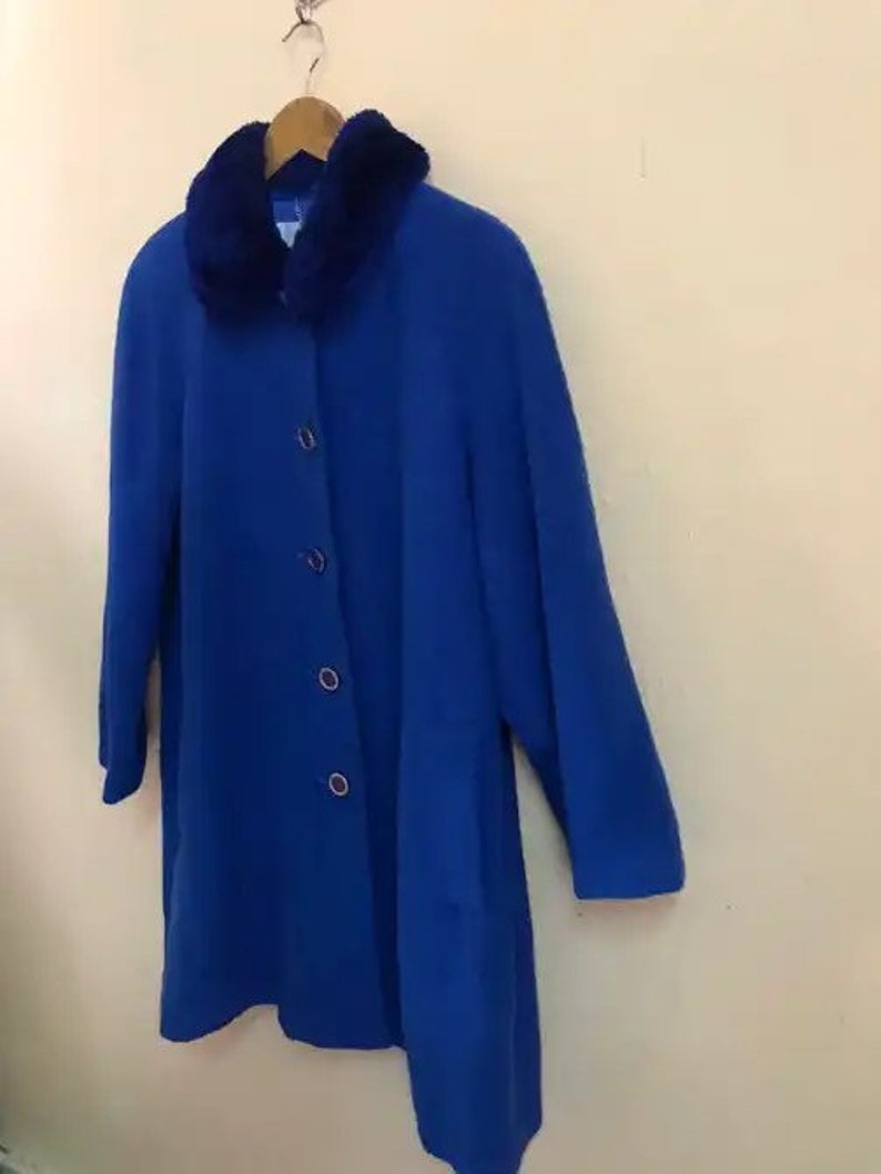 May include: A royal blue coat with a faux fur collar. The coat has a button closure and long sleeves.