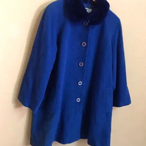 May include: A royal blue wool coat with a large faux fur collar. The coat has a button closure and a single pocket on the left side.