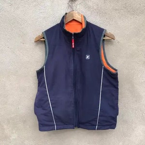 May include: A navy blue reversible vest with white piping and a zipper closure. The vest has a contrasting orange lining.