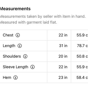 以下が含まれることがあります： 胸囲、着丈、肩幅、袖丈、裾幅の寸法をインチとセンチメートルで示した表です。