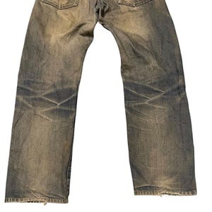 May include: Faded blue jeans with a worn appearance. The denim pants show signs of wear and tear, with visible fading and distressing throughout the fabric. The back pockets and waistband are visible.