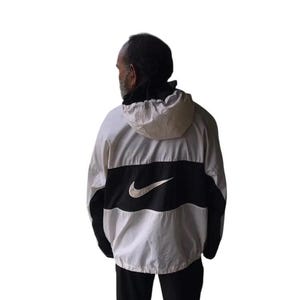May include: White, black, and gray Nike windbreaker jacket with a hood. The jacket features a large black stripe across the chest with the Nike swoosh logo in white. The sleeves and lower portion of the jacket are black.