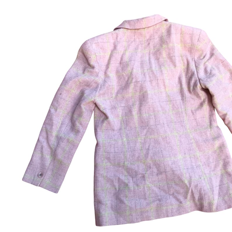 May include: A pink blazer with a light yellow plaid pattern. The blazer has a collar and long sleeves.