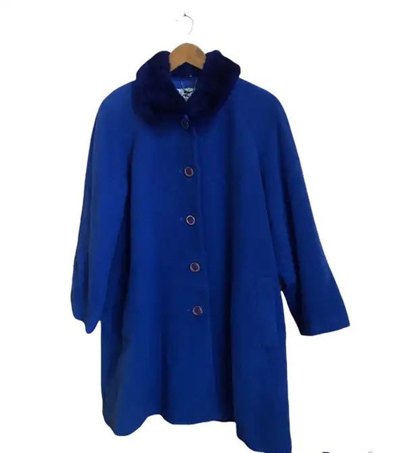 May include: A royal blue coat with a faux fur collar. The coat has a button closure and a pocket on the left side.
