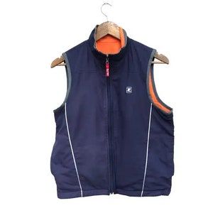 May include: A navy blue reversible vest with a zipper closure. The vest has a white stripe down each side and a small logo on the front. The vest is lined with orange fleece.