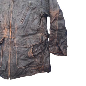 以下が含まれることがあります： ジッパー留めと複数のポケットが付いた茶色の革ジャンパー。ジャケットは使い古したような外観で、厚くて丈夫な革で作られています。
