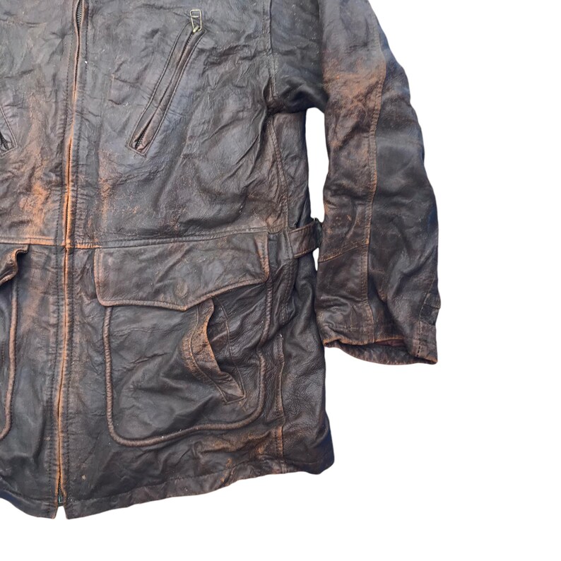 以下が含まれることがあります： ジッパー留めと複数のポケットが付いた茶色の革ジャンパー。ジャケットは使い古したような外観で、厚くて丈夫な革で作られています。
