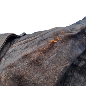 以下が含まれることがあります： 茶色の革ジャンパーのアップ。革は使い込まれており、経年変化が見られます。