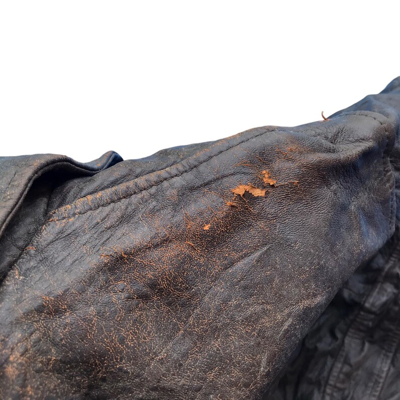 以下が含まれることがあります： 茶色の革ジャンパーのアップ。革は使い込まれており、経年変化が見られます。