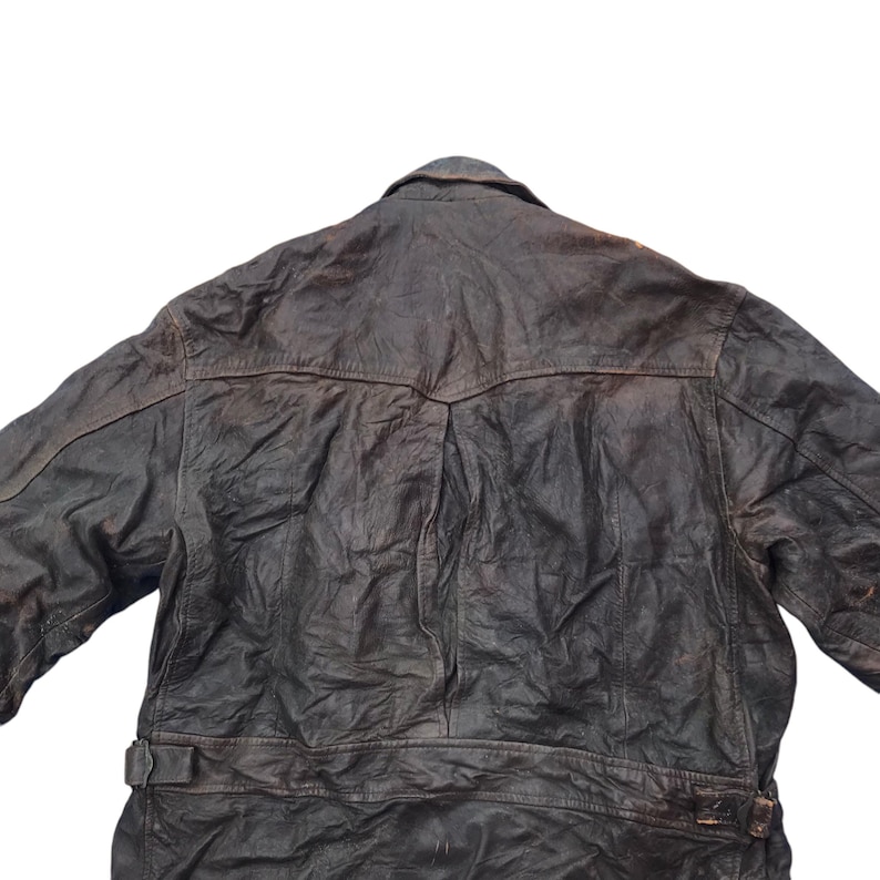 以下が含まれることがあります： ボタン留めとウエストにベルトが付いた茶色の革ジャンパー