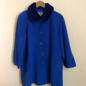 May include: A blue wool coat with a faux fur collar and button closure. The coat has a long, loose fit and is perfect for cold weather.