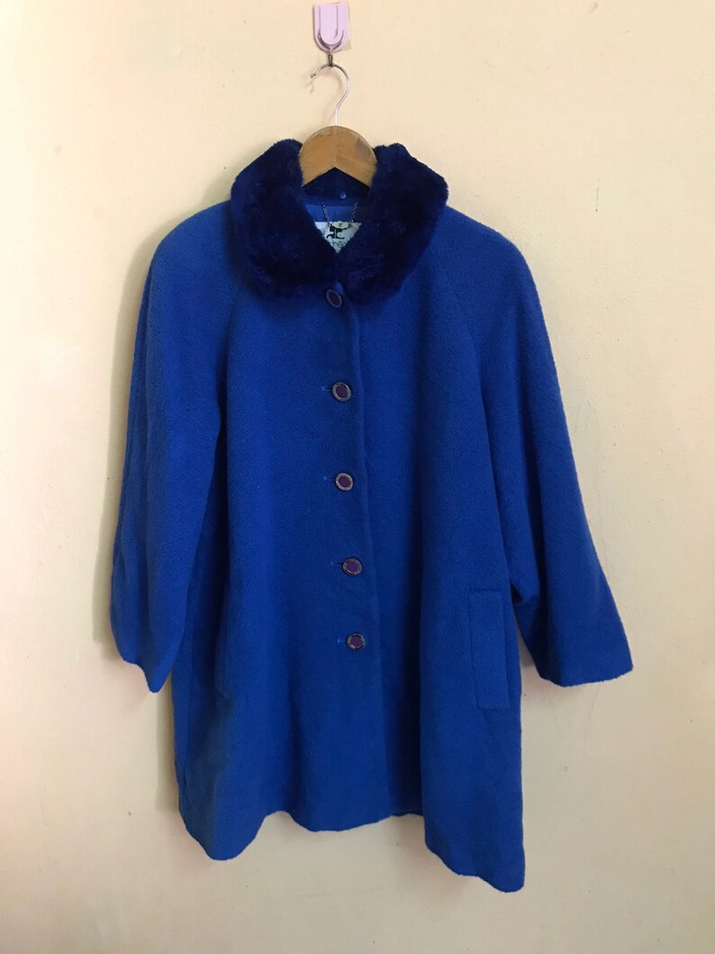 May include: A blue wool coat with a faux fur collar and button closure. The coat has a long, loose fit and is perfect for cold weather.