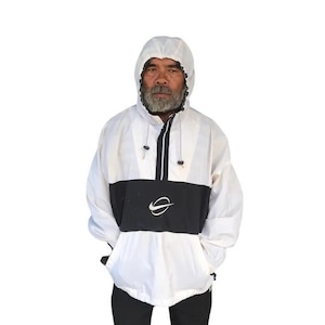 May include: White and black hooded anorak jacket with a front pocket and a black and white logo. The jacket has a drawstring hood and a half-zip closure. The model is wearing black pants.