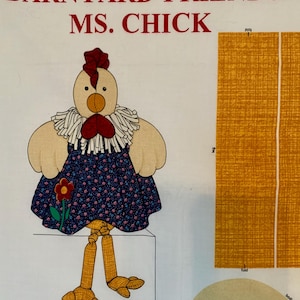 以下が含まれることがあります： 「Barnyard Friends」コレクションの「Ms. Chick」という名前の布製の鶏のイラスト。鶏はベージュの体、赤い鶏冠と肉垂れ、青い花柄のドレスを着ています。画像には、プロジェクト用の布の切れ端も含まれています。