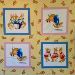 Può includere: Un pannello di tessuto con illustrazioni di conigli. Il pannello ha uno sfondo giallo con motivi di conigli ripetuti. Quattro illustrazioni incorniciate mostrano conigli in diverse scene, con bordi blu e rosa.