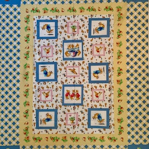 May include: A fabric panel featuring a repeating pattern of framed illustrations of rabbits and birds. The central panel has a white background with small brown and red illustrations. The border is yellow and blue with a checkered pattern and fruit illustrations.