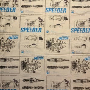 May include: White fabric with a repeating pattern of blueprints and schematics of the Millennium Falcon and other spacecraft. The word "SPEEDER" is printed in blue, along with other text and illustrations.