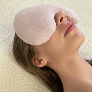 Puede incluir: Una máscara para los ojos de lino rosa para dormir o relajarse. La máscara tiene forma de lágrima y una textura suave y cómoda.