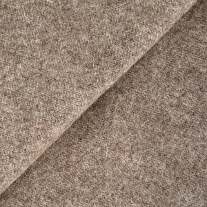 May include: Close-up of a brown, textured fabric with a fuzzy surface. The fabric is folded in half, showing the texture and color of the material.