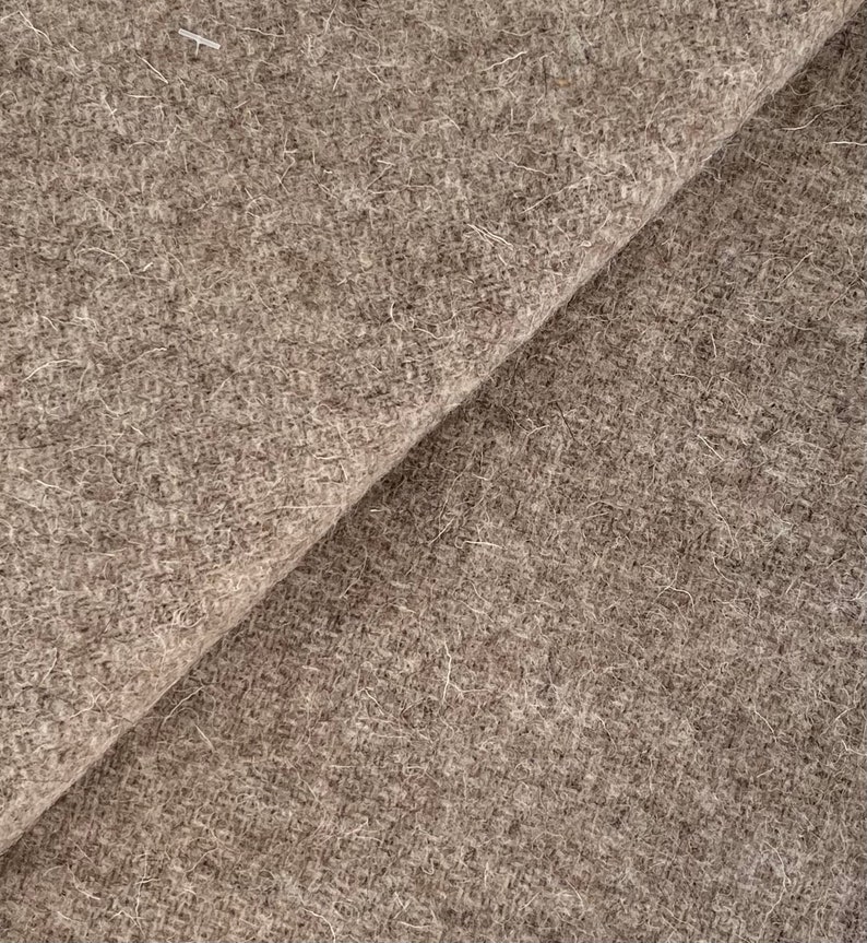 May include: Close-up of a brown, textured fabric with a fuzzy surface. The fabric is folded in half, showing the texture and color of the material.