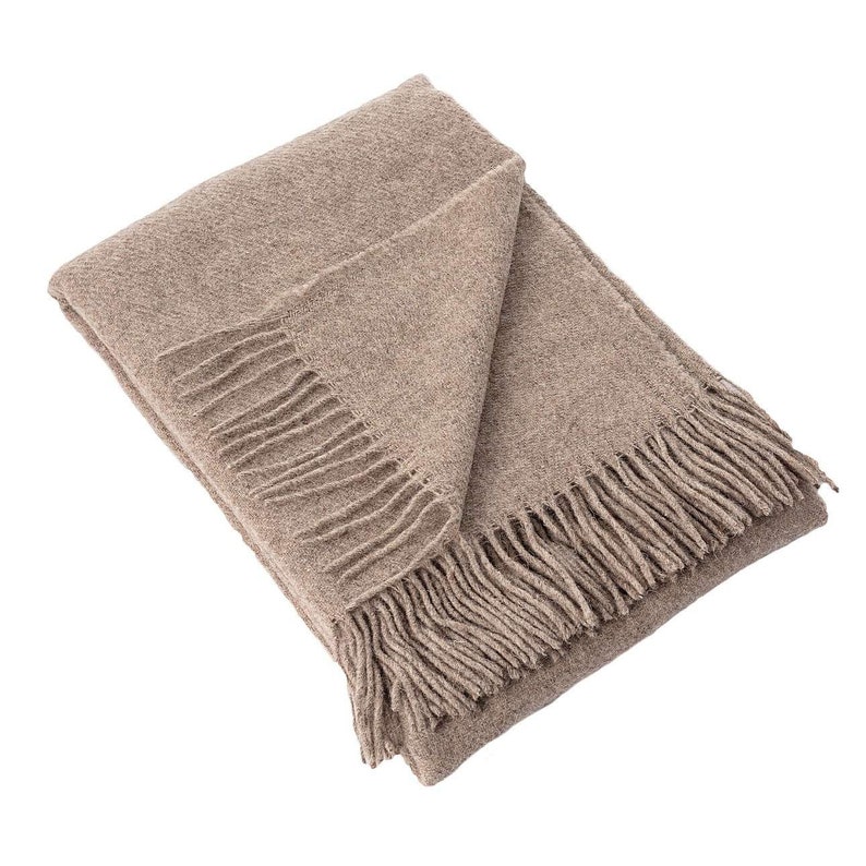 May include: A brown throw blanket with fringe on all sides. The blanket is folded in half and laid flat on a white background.