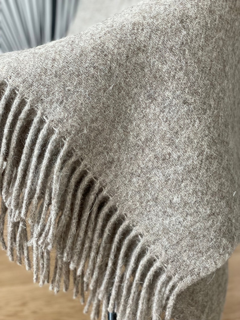 May include: A soft, brown throw blanket with a fringe border. The blanket is made of a fuzzy material and has a subtle texture.