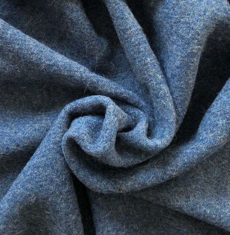 May include: Close-up of a soft, blue fabric with a fuzzy texture. The fabric is folded and draped, creating a swirling pattern.