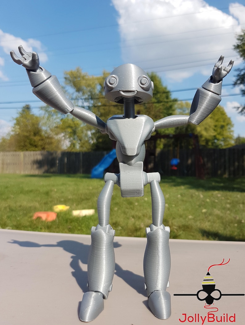 May include: A silver 3D printed robot with articulated limbs and a friendly face. The robot is posed with arms raised and a wide smile.