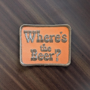 May include: Orange fabric patch with brown embroidered text that reads "Where's the Beer?"