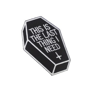 May include: Black and white embroidered iron-on patch shaped like a coffin with the text "This is the last thing I need" and a small cross.