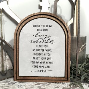 Puede incluir: Un letrero enmarcado en madera con el texto "BEFORE YOU LEAVE THIS HOME always remember I LOVE YOU. NO MATTER WHAT. I BELIEVE IN YOU. TRUST YOUR GUT. FOLLOW YOUR HEART. COME HOME SAFE. xoxo" en escritura negra.