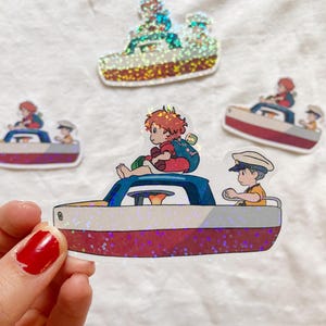 Può includere: Una collezione di adesivi glitterati raffiguranti una barca dei cartoni animati con personaggi. La barca è rossa e blu, con un personaggio con un cappello da marinaio. Gli adesivi sono su sfondo bianco.