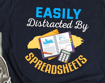 Puede incluir: Una camiseta azul marino con el texto "EASILY Distracted By SPREADSHEETS" en blanco y azul. Un diseño de salpicaduras amarillo y naranja rodea un cuaderno y una calculadora.