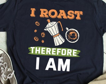May include: A navy blue t-shirt with a white graphic that says "I roast therefore I am". The graphic also includes a coffee pot and a cup of coffee.