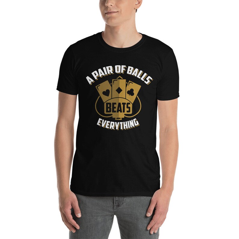 May include: A black t-shirt with a gold graphic of three playing cards with the text "A Pair of Balls Beats Everything".