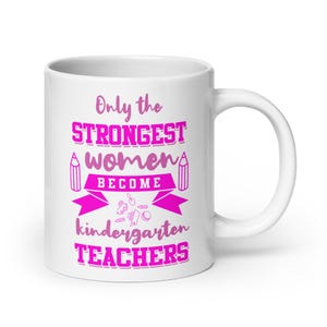 May include: A white ceramic mug featuring bright pink text that reads: Only the STRONGEST women BECOME kindergarten TEACHERS. The design includes small illustrations of pencils and school supplies arranged around the bold, capitalized lettering.
