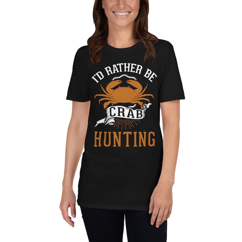 May include: Black t-shirt with a white graphic that says "I'd rather be crab hunting". The graphic features a cartoon crab with a banner that says "crab".