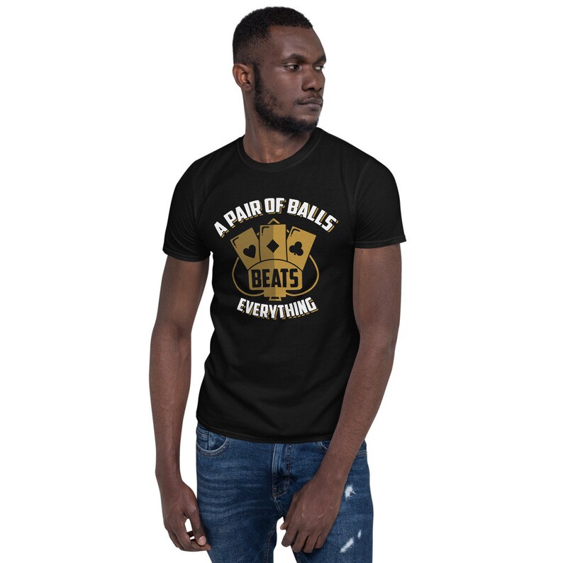 May include: A black t-shirt with a gold graphic design that says "A Pair of Balls Beats Everything". The graphic features three playing cards in a crown shape.