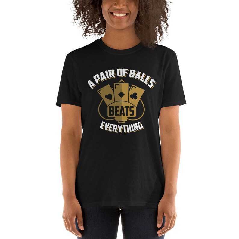 May include: A black t-shirt with a gold graphic design that says "A Pair of Balls Beats Everything". The graphic features three playing cards in a diamond shape.