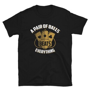 May include: Black t-shirt with a gold graphic of three playing cards with the text "A Pair of Balls Beats Everything".