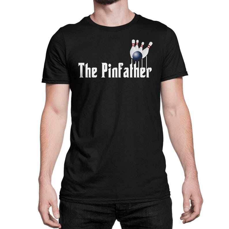 May include: Black t-shirt with a white graphic of bowling pins and a bowling ball. The text "The Pinfather" is printed in white below the graphic.