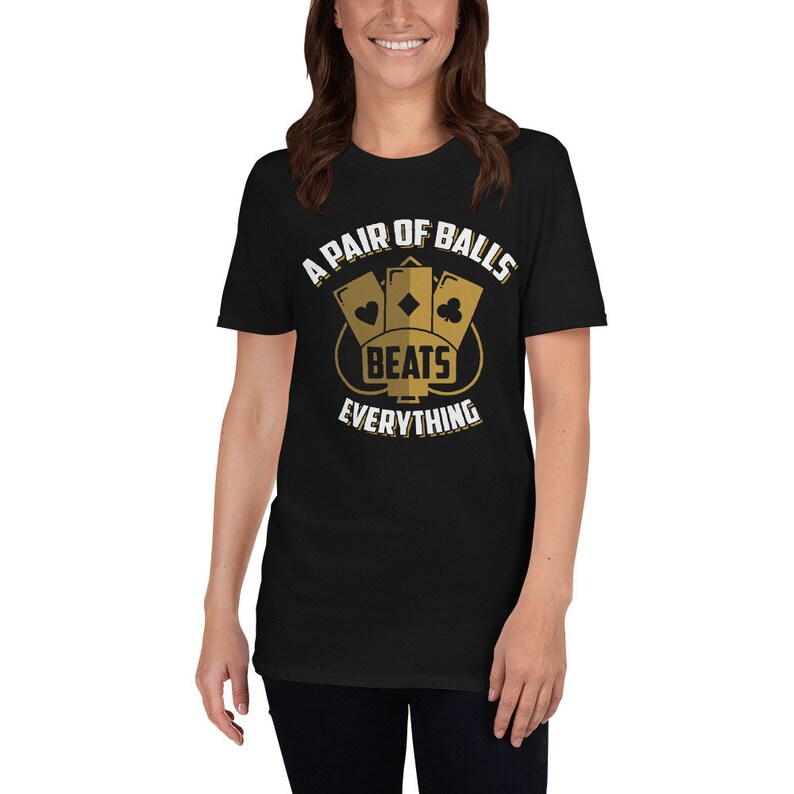 May include: A black t-shirt with a gold graphic that says "A Pair of Balls Beats Everything". The graphic features three playing cards with hearts, diamonds, and clubs.