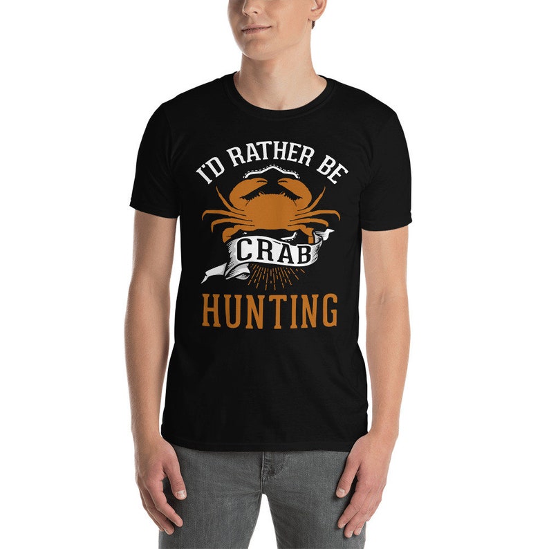 May include: Black t-shirt with a white graphic design that says "I'd rather be crab hunting". The graphic features a crab with a white banner that says "crab" and a sunburst design.